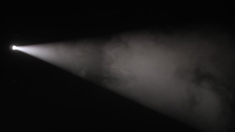 Close-up of a white spotlight shining on the stage in the dark.