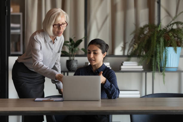 Elder coworker giving advice, explaining work process to Indian employee