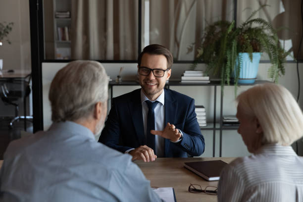 Happy confident lawyer, Real Estate Agent, notary, financial advisor giving consultation Happy confident lawyer, Real Estate Agent, notary, financial advisor giving consultation, legal advice to senior couple of clients about medical insurance, wills, house buying or selling, savings, investment estate planning attorney stock pictures, royalty-free photos & images