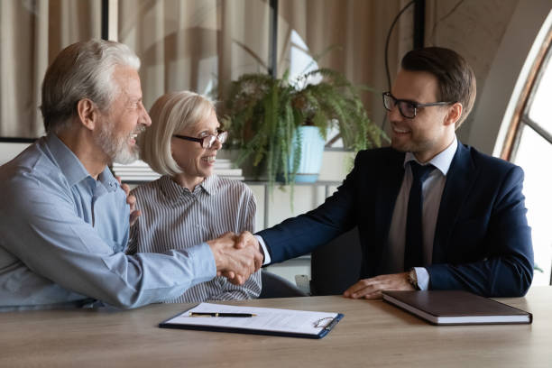 istock Happy elderly married couple shaking hands with Real Estate Agent 1330082277