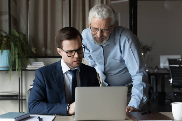 istock Older professional giving help, advice to young coworker 1330082318