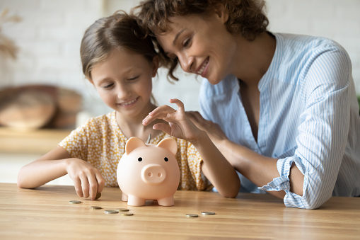 Cuidada madre joven enseñando a la hija de un niño pequeño en edad preescolar a ahorrar dinero. photo