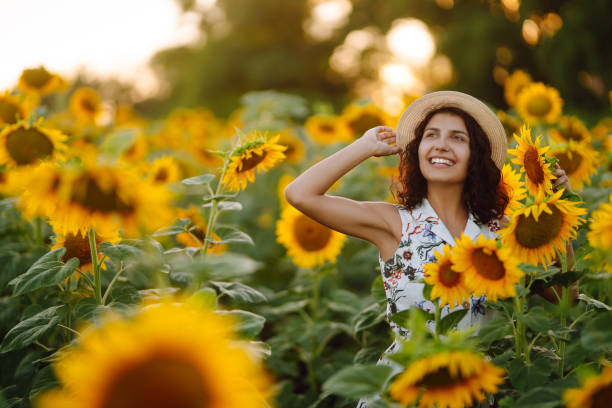 istock Young woman strolling through field with sunflowers at sunset. 1330087902