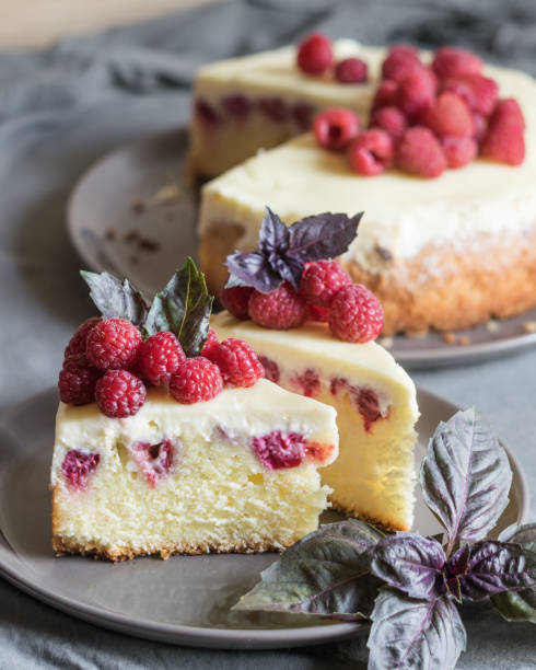 istock Raspberry cheesecake slices with fresh raspberries and bazil leaves on a grey plate, whole cheesecake in background. Selective focus 1330091017