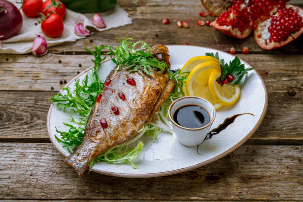 Dorado on grill on a white plate on old wooden table