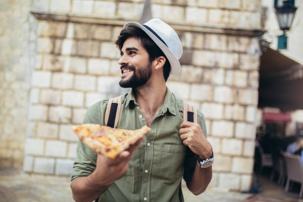 istock Young man eats a piece of appetizing pizza 1330094531
