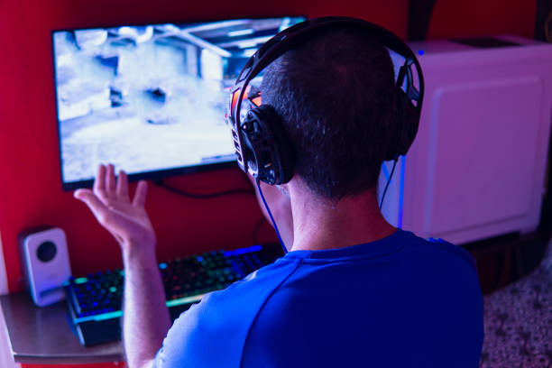 istock Young man with headphones playing video games on a gamer desktop computer gesturing in frustration. 1330094554