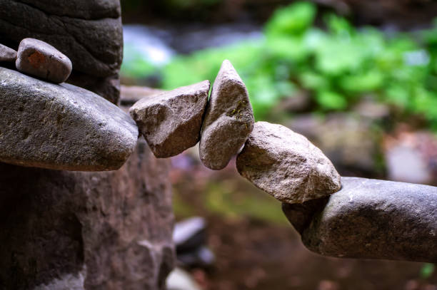 ponte di roccia, piramide, arte del bilanciamento della roccia. primo-up di una pila di pietre in perfetto equilibrio in una foresta di montagna. raggi solari. meditazione, equilibrio, pace. passatempo. - ponticello di strumento musicale foto e immagini stock