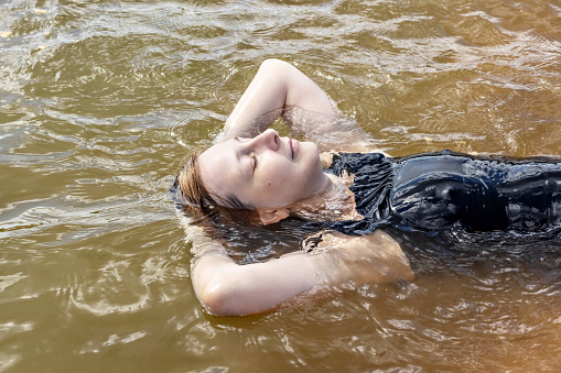 Portrait of a young woman close-up in the water. Swimming in the lake.