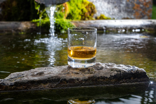 glass of strong scotch single malt whisky served on old stone reservoir for water from mountain spring - spey scotland stockfoto's en -beelden