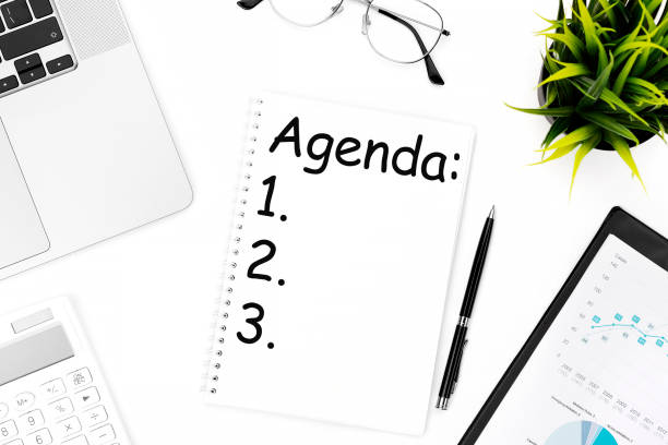 istock Text AGENDA on notebook. Laptop, calculator, clipboard for chart, glasses, pen and plant. Flat lay, Business concept. 1330101653