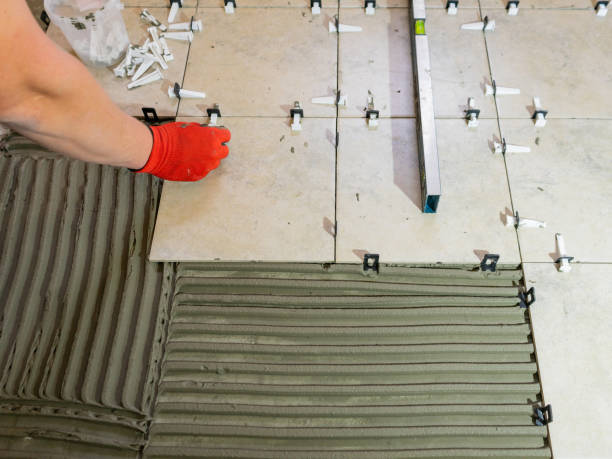 istock Workers are using plastic clamps and wedges to leveling the ceramic tile on the floor. Tile leveling system. 1330105081