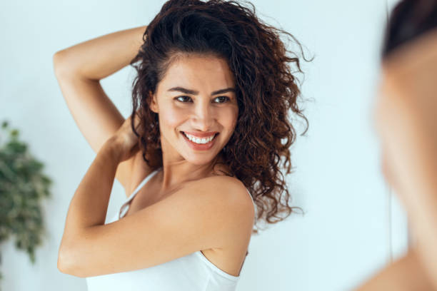 istock Beautiful young woman looking herself while smiling at mirror at home. 1330107115