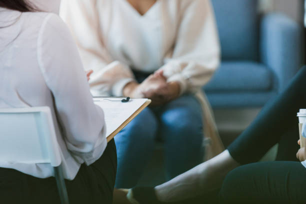 istock Women in group therapy listen to unrecognizable therapist with clipboard 1330107331