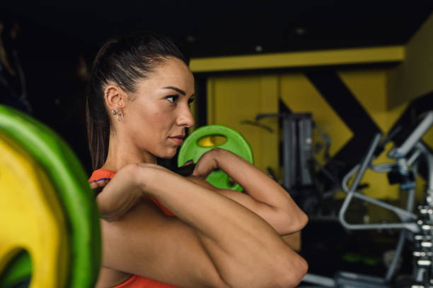 Strong women bodybuilder doing overhead with heavy barbell in modern gym. Functional training class. Bodybuilding and fitness. Healthy lifestyle.