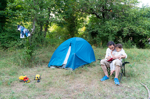 Çocukları ile kamp yapan baba, günlük notlar almaktadır. Çocukları doğaya alıştırmak ve doğayı tanıtmak amacıyla yapılmış bir gezi. Gün ışığında full frame makine ile çekilmiştir.