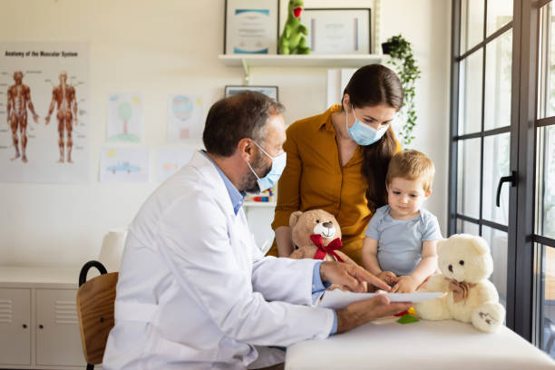 mother with protective face mask and baby son at a doctor´s appointment - pediatrician imagens e fotografias de stock