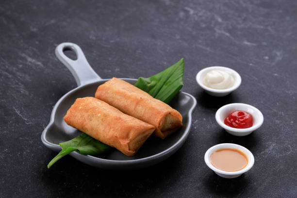 istock Deep Fried Spring Rolls, Popular as Lumpia or Popia. Served on Grey Pan Plate, Black marble table. Copy Space for Text 1330127112