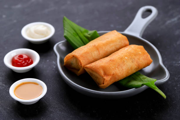 istock Deep Fried Spring Rolls, Popular as Lumpia or Popia. Served on Grey Pan Plate, Black marble table. Copy Space for Text 1330127249