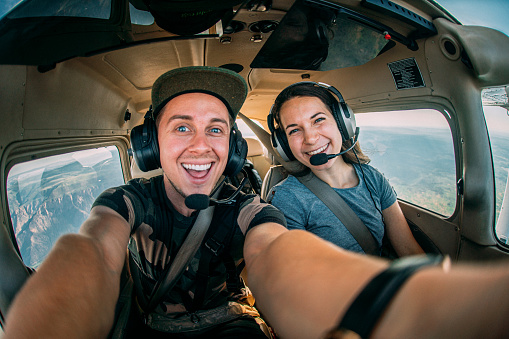 Dos alegres amigos adultos jóvenes juntos en la cabina volando un pequeño avión de un solo motor photo