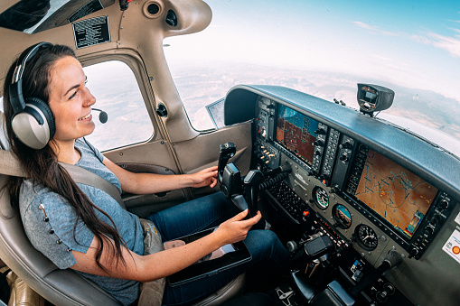 Toma gran angular de una joven piloto adulta alegre e instructora de vuelo sonriendo y volando un pequeño avión monomotor photo