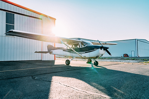 Sunrise Shot of a Small Single Engine Airplane Outdoors in Front of a Hangar