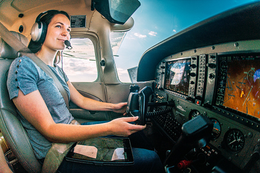Wide Angle Shot of a Cheerful Young Adult Female Pilot Flying a Small Single Engine Airplane