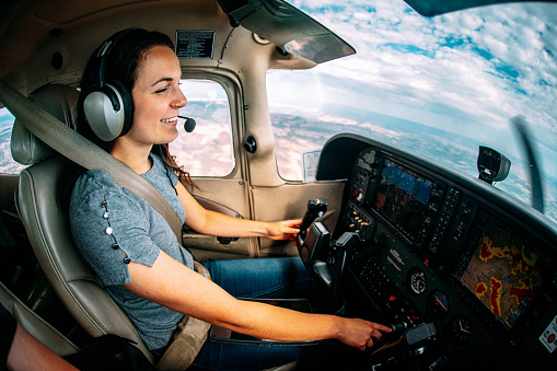 Wide Angle Shot of a Cheerful Young Adult Female Pilot Flying a Small Single Engine Airplane