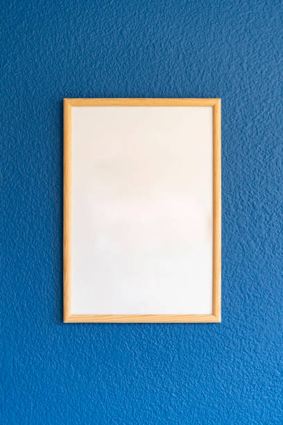 istock Empty wooden frame, poster white blank canvas mock up on a blue wall, living room template front view 1330134402