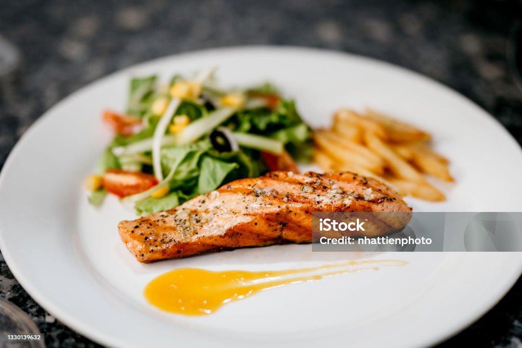 A white plate of the pan seared salmon fillet with lemon butter sauce Grilled Salmon Stock Photo