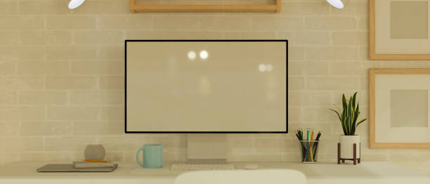 istock Desktop computer blank screen and frames mock up in minimal work space with office supplies and decorations on white table and brick wall 1330140422