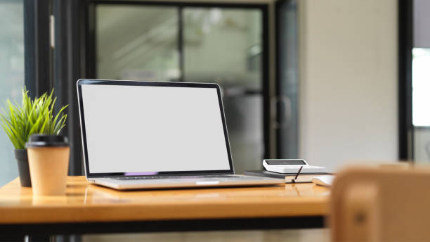 istock Laptop mock up with office supplies with office interior in the background, working space concept 1330141111
