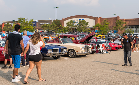 Homestead, Pennsylvania, USA July 21, 2021 People in the parking lot admiring cars at a summer vintage car show. The Pittsburgh Grand Prix, a yearly event for the past 38 years holds public car shows leading up to the race in the Pittsburgh area, including this one.