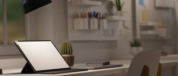 istock Portable tablet and keyboard on desk, low light from table lamp with modern work space 1330144426