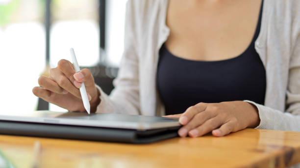 istock Close up front view of female using stylus pen with tablet for her graphic work 1330145219