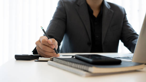istock Cropped shot businessman in suit making note on notebook and working with laptop. 1330147951