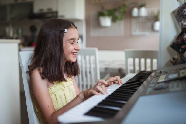 Happy young girl enjoying practicing piano Jolly young musician practicing piano girl playing piano stock pictures, royalty-free photos & images
