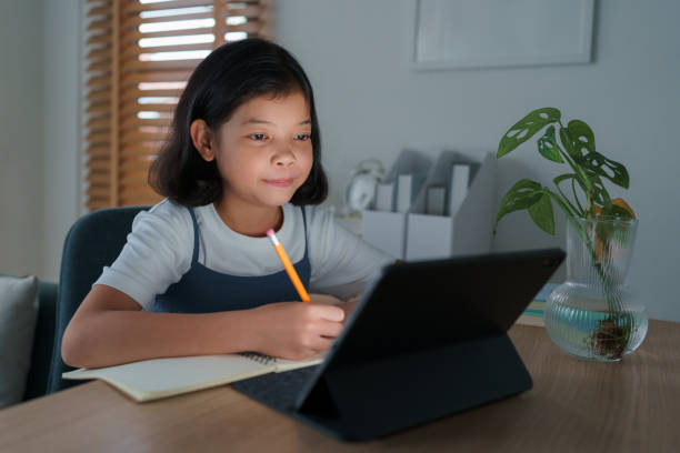 istock asian little girl using tablet digital at home night 1330153575