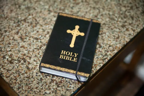 Black bible with ornate gold cross and the words Holy Bible on the cover sitting on the counter