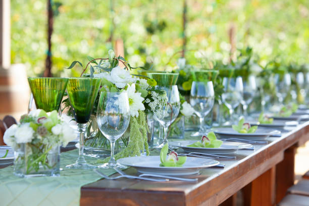Long wood table and chairs in vineyard set for party with flowers, glassware, wine glasses, plates and silverware stock photo