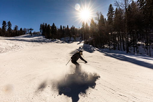 Female skier skiing down the hill in winter day. Copy space.