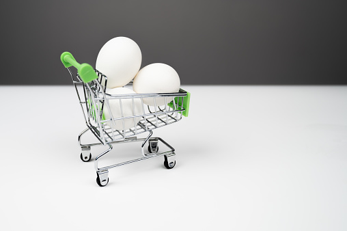 Three chicken white eggs in a shopping trolley, side view. High quality photo