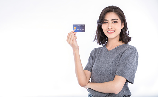 Portrait of young smiling beautiful Asian woman presenting credit card in hand showing trust and confidence making payment, online shopping telemarketing e-commerce concept with copy space
