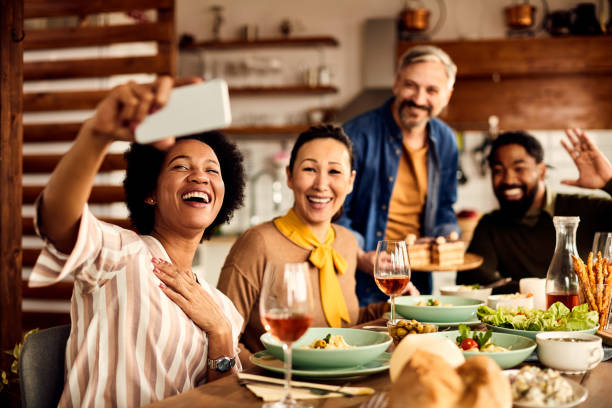 istock Cheerful multi-ethnic group of friends taking selfie during a meal at dining table. 1330157594