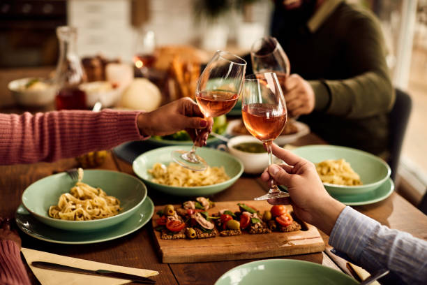istock Close-up of people toasting with wine during a meal at dining table. 1330157609