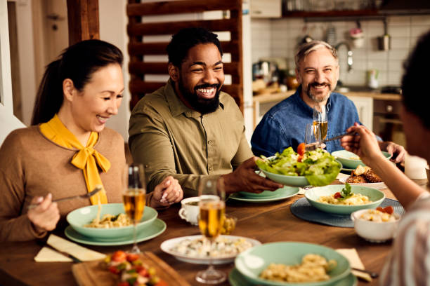 istock Multi-ethnic group of happy friends enjoying while eating lunch together at dining table. 1330157616