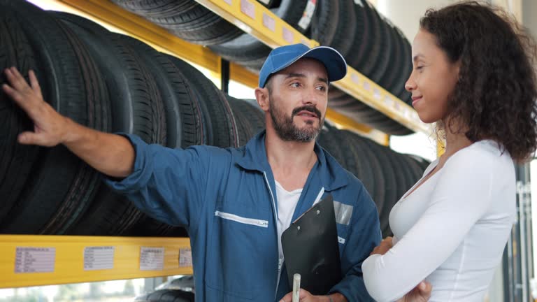 Salesman mechanics of tires service of product to customer in auto service shop.