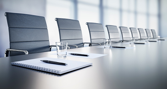 Close up of a large conference table with chairs in a meeting room in the high-rise office building, view of the skyline