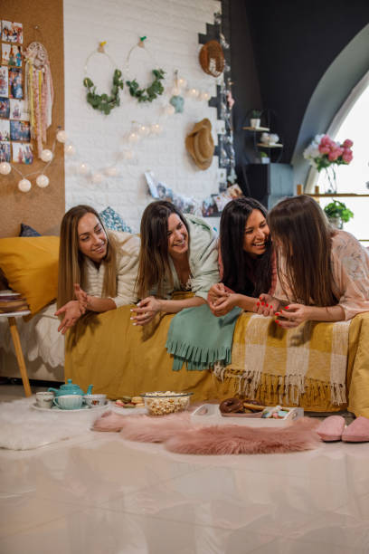 istock Four girlfriends lying on bed and hanging out during a sleepover 1330161717