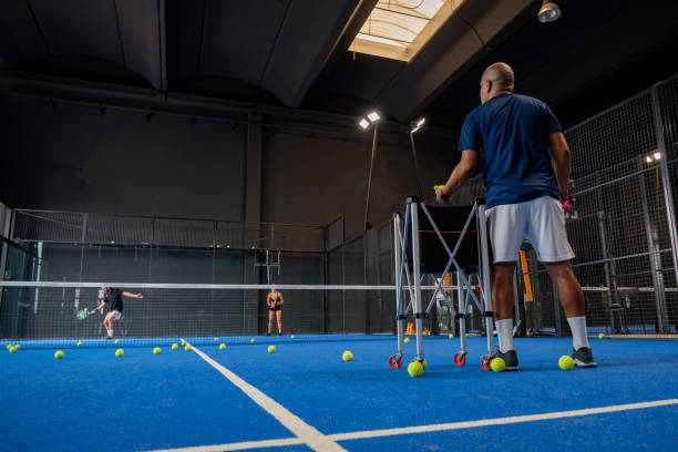 人間にパデルクラスを教えるモニター、彼の学生 - トレーナーは、屋内テニスコートでパデルをプレイする方法を少年に教えます - tennis indoors sport leisure games ストックフォトと画像